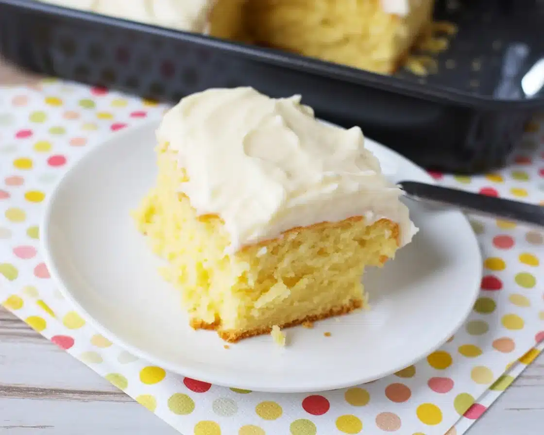 Delicious Pineapple Sunshine Cake topped with whipped cream and tropical fruits.